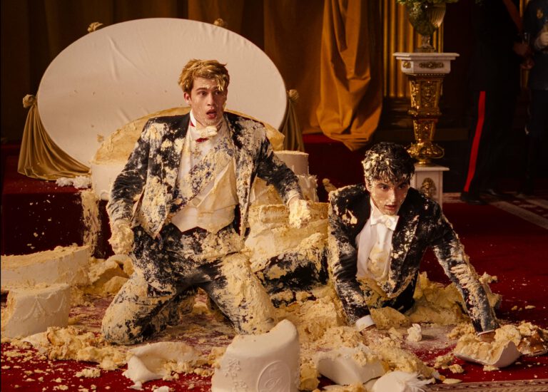 A still form the new red white and royal blue movie with Taylor Zakhar Perez and Nicholas Galitzine covered in cake